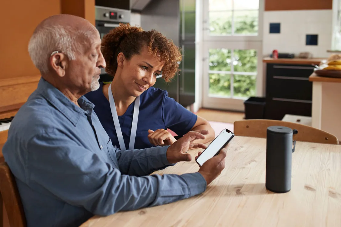 A care worker and an older adult reviewing feedback together on a tablet